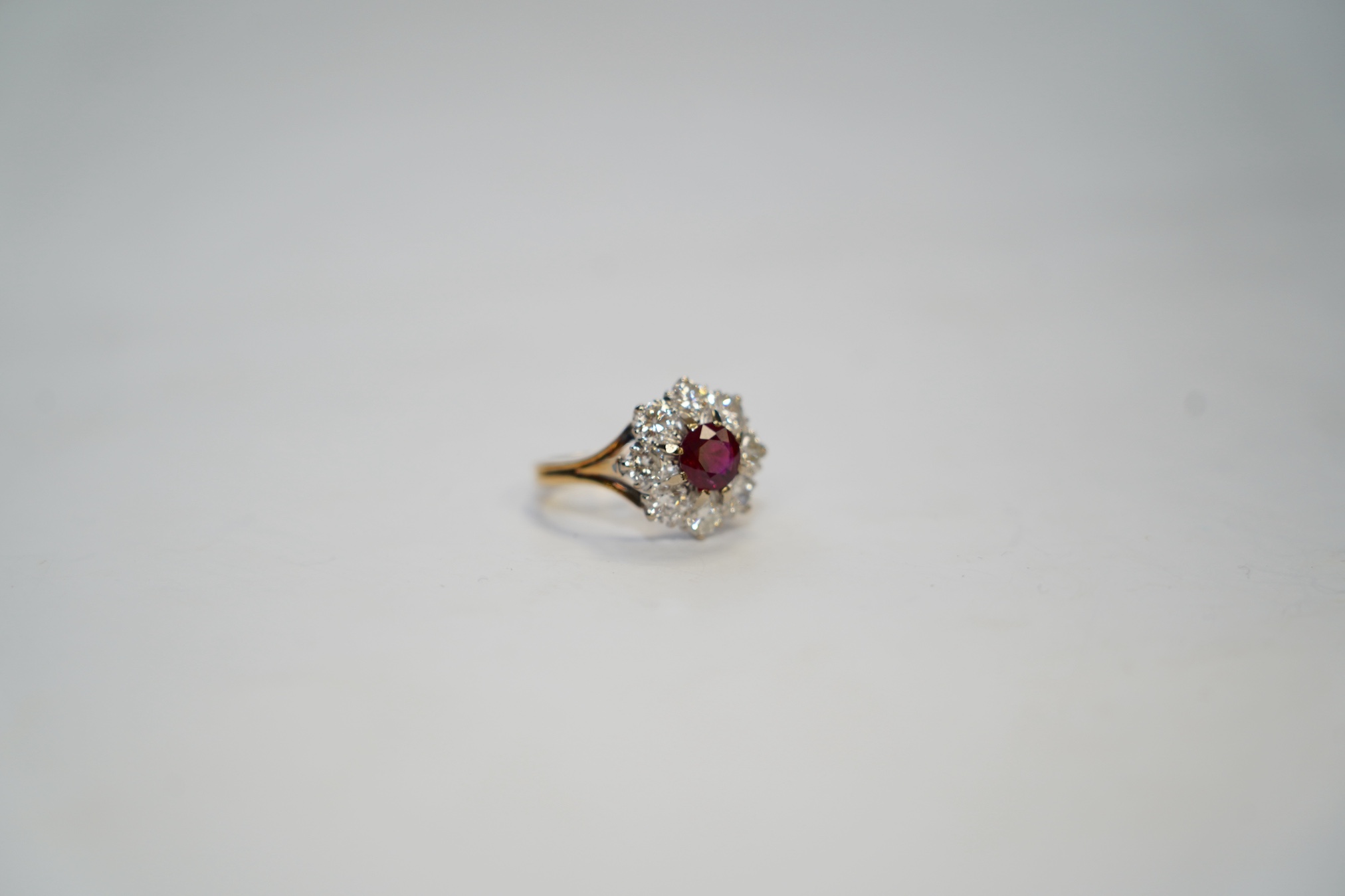 An 18ct gold, single stone ruby and eight stone diamond set flower head cluster ring, size P, gross weight 6.5 grams. Condition - fair